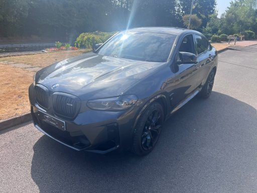 Grey BMW parked on a quiet road with greenery in the background.