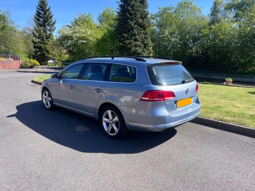 Silver estate car parked in a sunny, green environment.