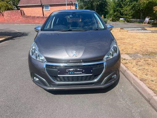Grey Peugeot parked on a quiet road with greenery in the background.