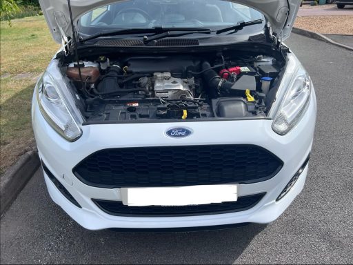 Front view of a white Ford car with the bonnet open, revealing the engine compartment.