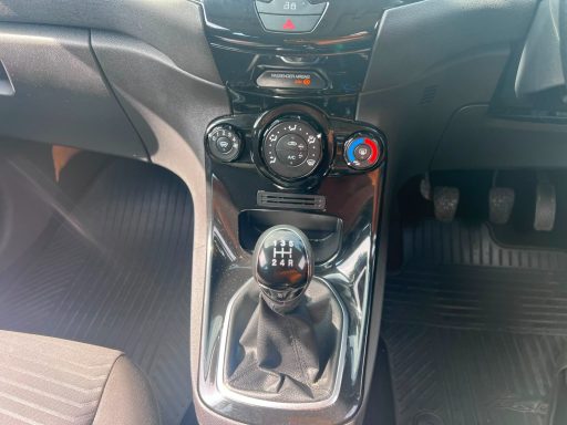 Car interior with gear shift, dashboard controls, and leather upholstery.