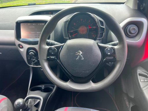 Car interior featuring a steering wheel, dashboard display, and controls.