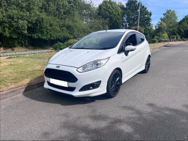 White Ford Fiesta with black alloy wheels parked on a quiet road.