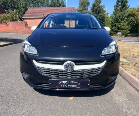 Front view of a black Vauxhall Corsa on a quiet road.