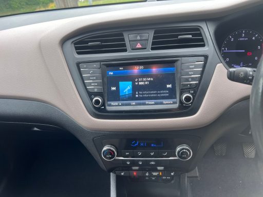 Car dashboard with a touchscreen display showing music information and controls.